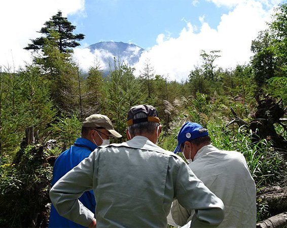 スタッフの打合せ風景の奥に雲間から少し見える富士山頂（2022年9月10日）